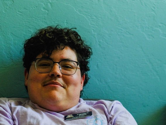 Francisco leaning back with his arms folded, sitting against a teal wall. He is smiling at the camera.