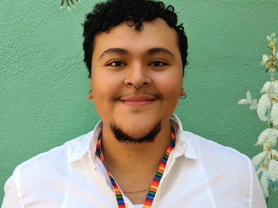 Graduate student, Lupe, standing in front of light green background