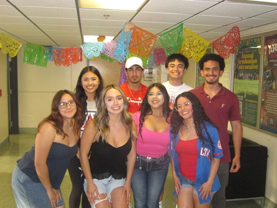 Latine Student Association group of students standing in front of a hallway 