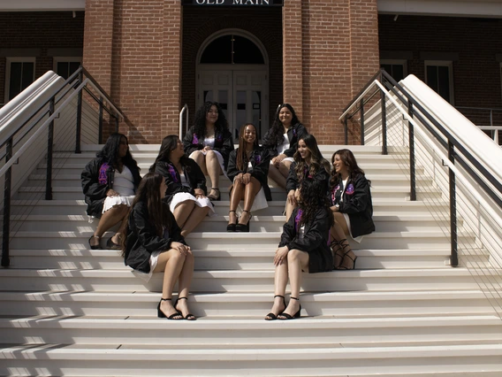 Members of Sigma Lambda Gamma sitting on the steps of Old Main