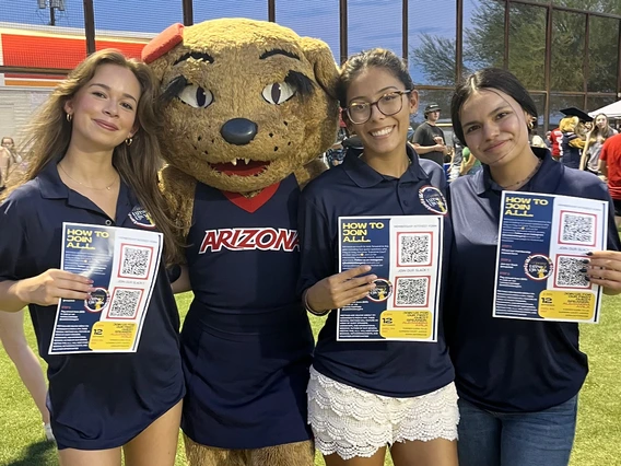 3 students standing with Wilma the UA mascot