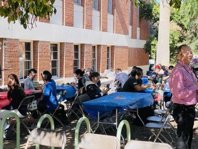 Tables outside, students sitting down on chairs eating