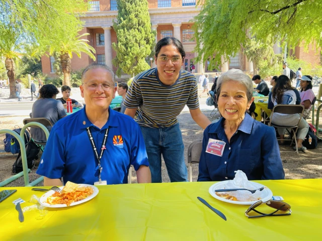 Student standing, two people sitting down at AROMAS