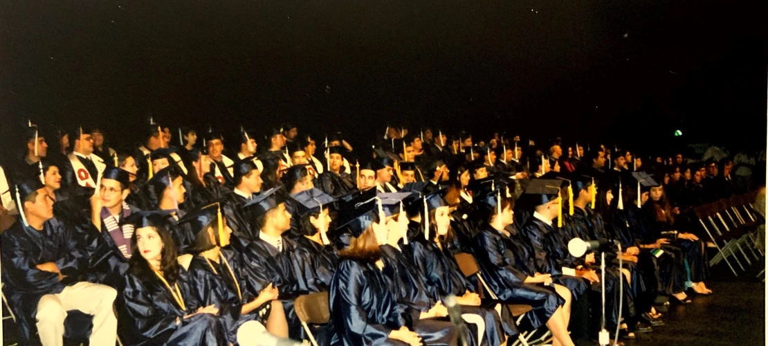 A group of students wearing blue graduation gowns sitting down for convocation