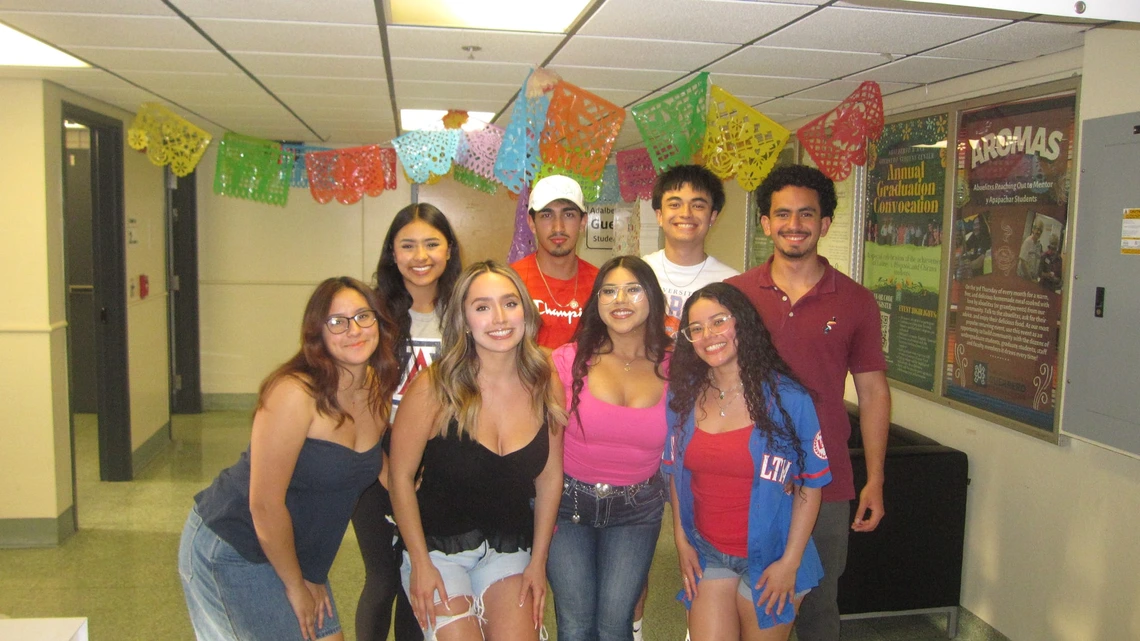 Latine Student Association group of students standing in front of a hallway 