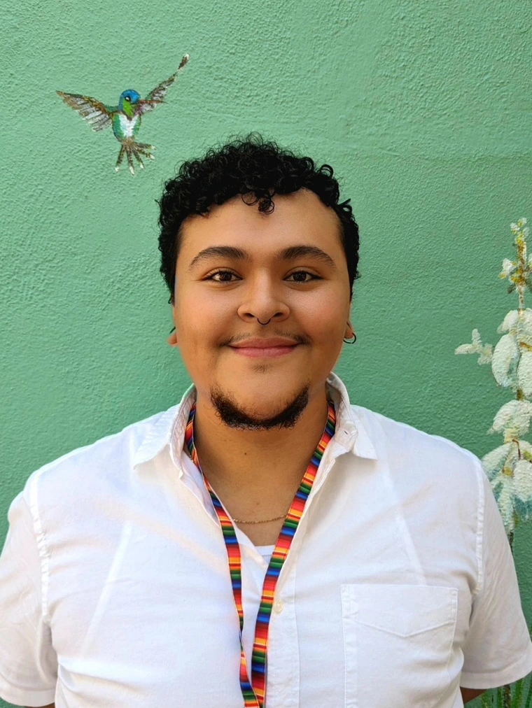 Graduate student, Lupe, standing in front of light green background