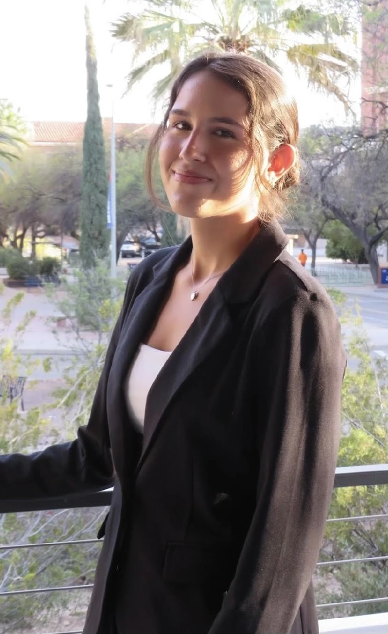 Image of student standing in front of rail, wearing black blazer