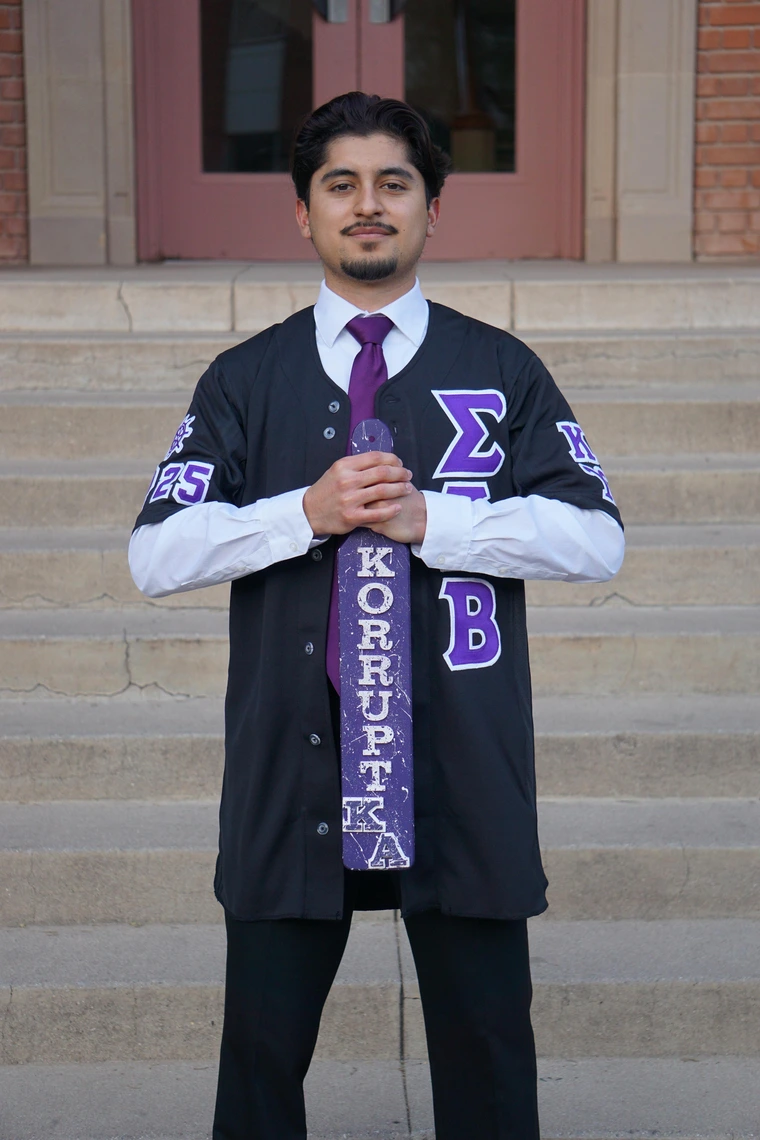 Student wearing greek letters, standing in front of building