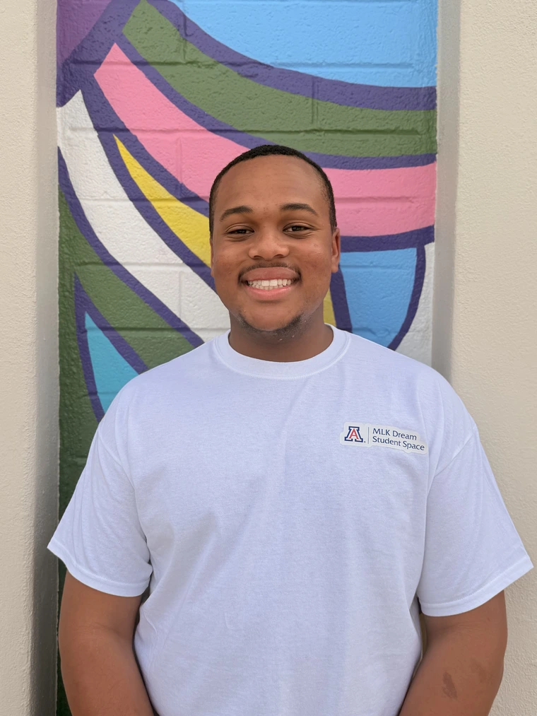 African American male student with close cut fade haircut, wearing a white tee shirt that says "MLK Dream Student Space" in the upper left corner
