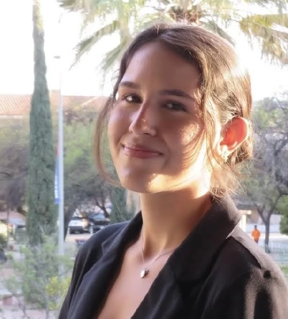 Image of student standing in front of rail, wearing black blazer