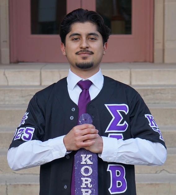 Student wearing greek letters, standing in front of building