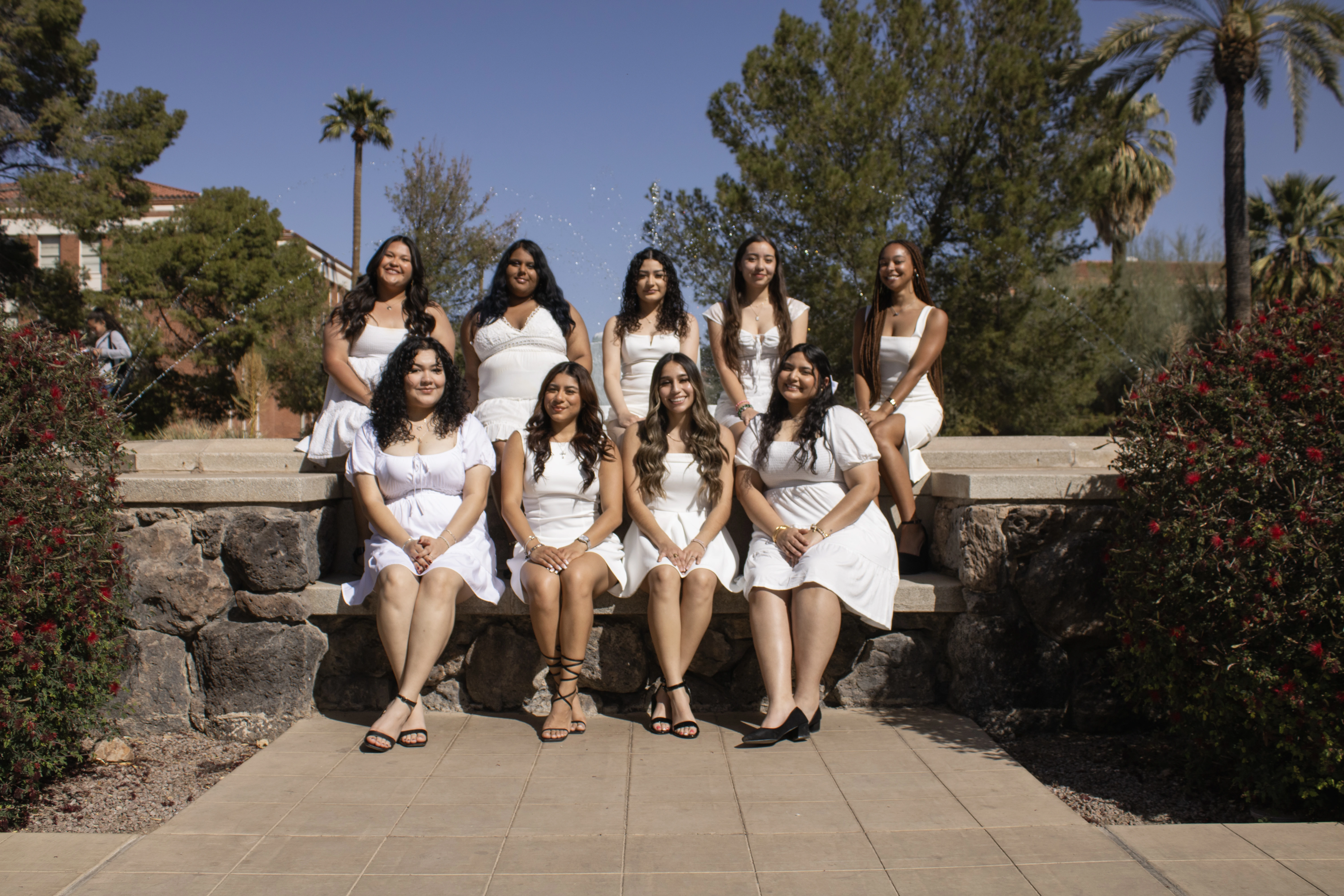 9 members of Sigma Lambda Gamma sitting down by Old Main