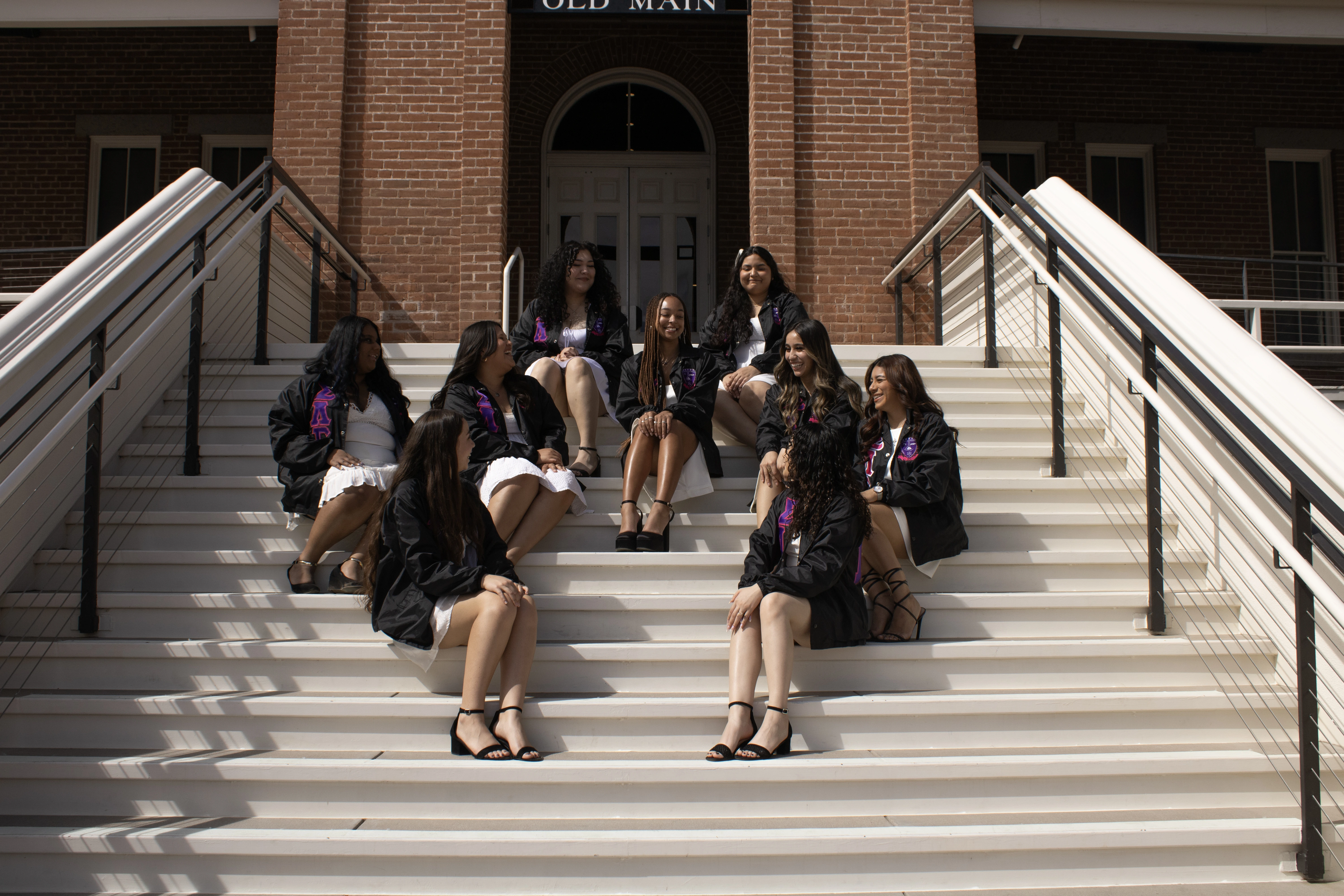 Members of Sigma Lambda Gamma sitting on the steps of Old Main