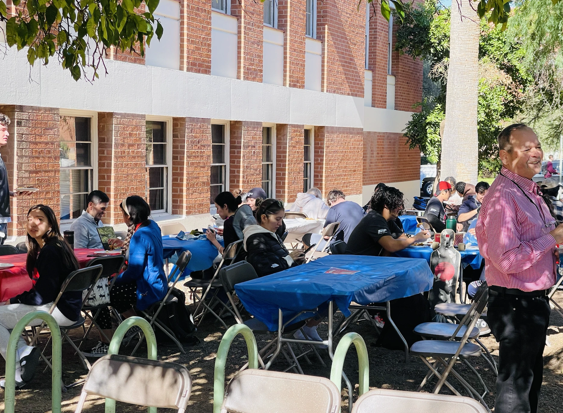 Tables outside, students sitting down on chairs eating