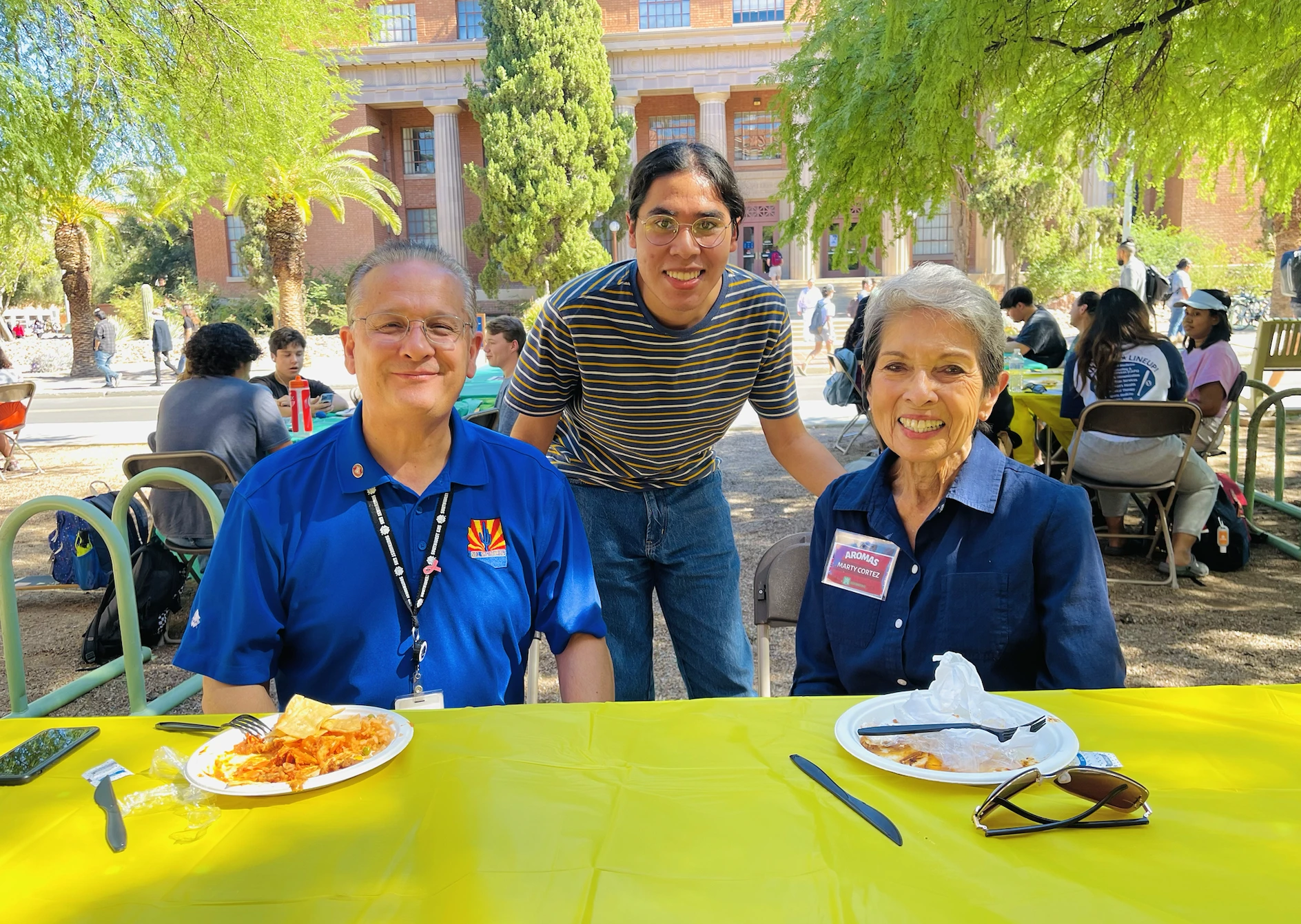 Student standing, two people sitting down at AROMAS