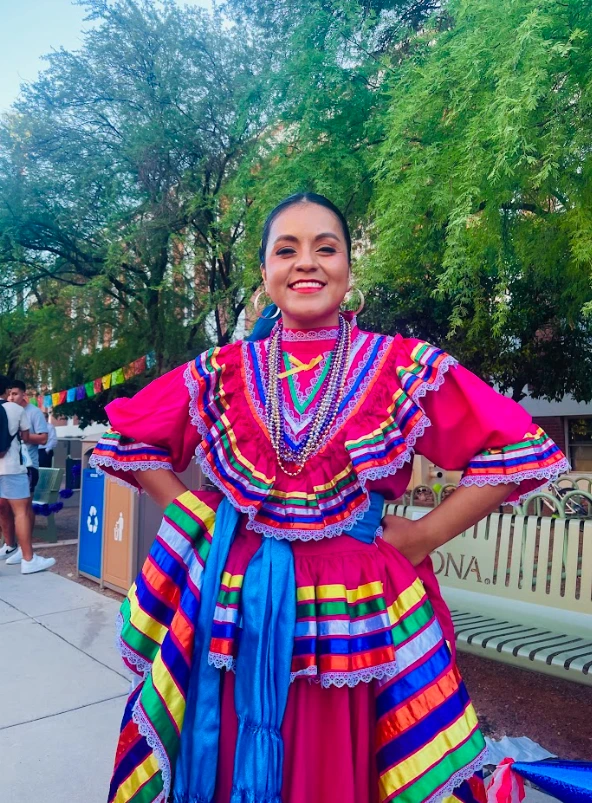 Folklorico Dancer wearing a traditional bright pink dress with colorful ribbons
